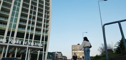 A modern urban street scene in Valdivia with pedestrians and high-rise building under clear sky.