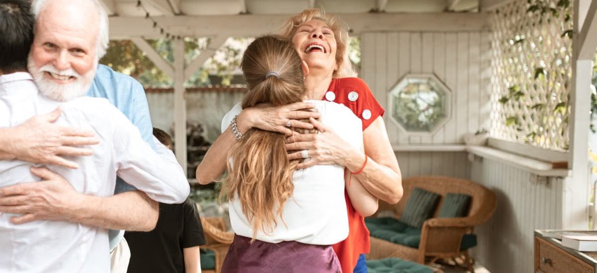 A heartwarming reunion with family members hugging and smiling in a cozy indoor setting.